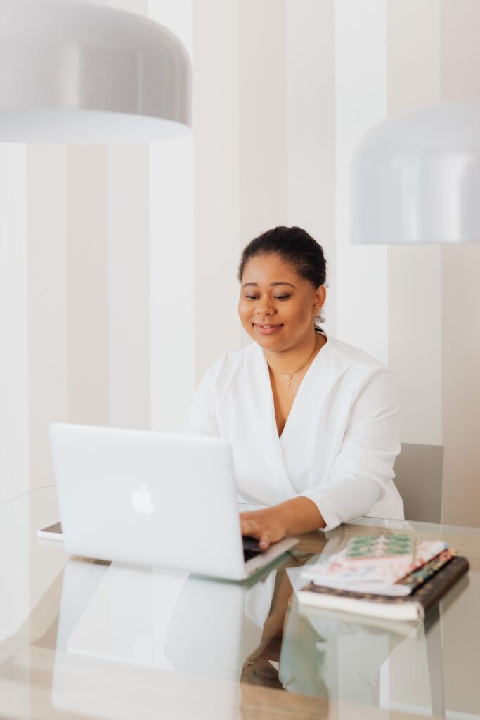 A creative entrepreneur smiling while working on a laptop—illustrating confidence and ease through organized systems.