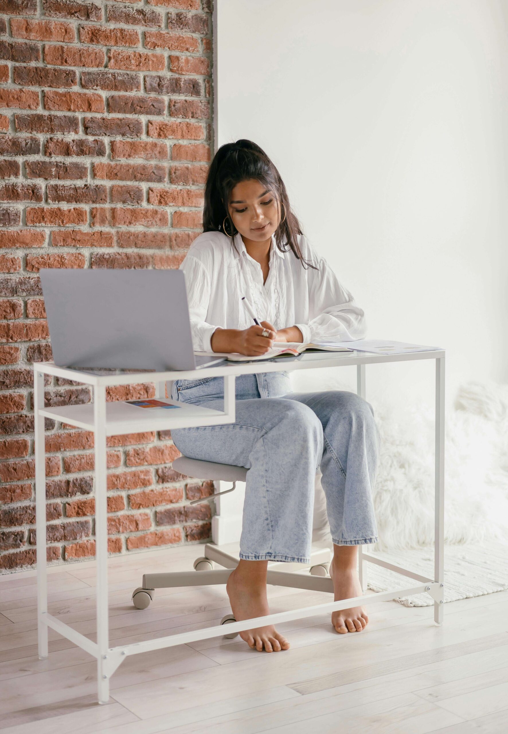 A designer writing notes beside an open laptop—symbolizing thoughtful website planning and the creative process behind web design for women entrepreneurs.