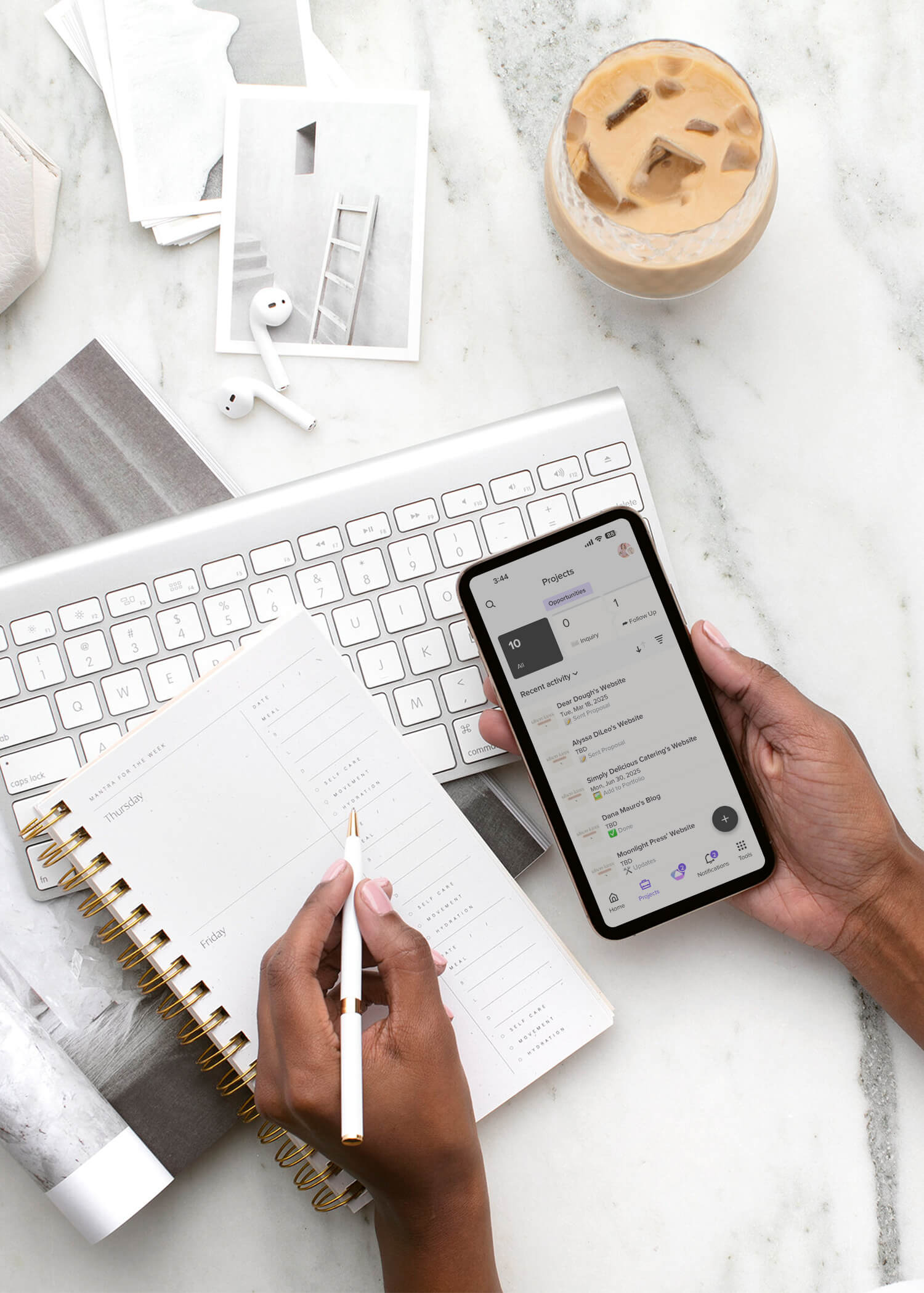 A styled workspace with a keyboard, coffee, phone, and open planner—capturing the organized calm of a streamlined digital workflow for creative entrepreneurs.