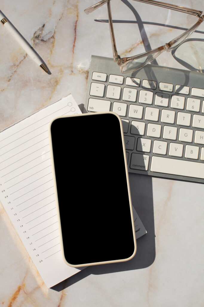 Flat lay of creative tools— computer, notebook, and phone—symbolizing an organized tech stack for entrepreneurs.