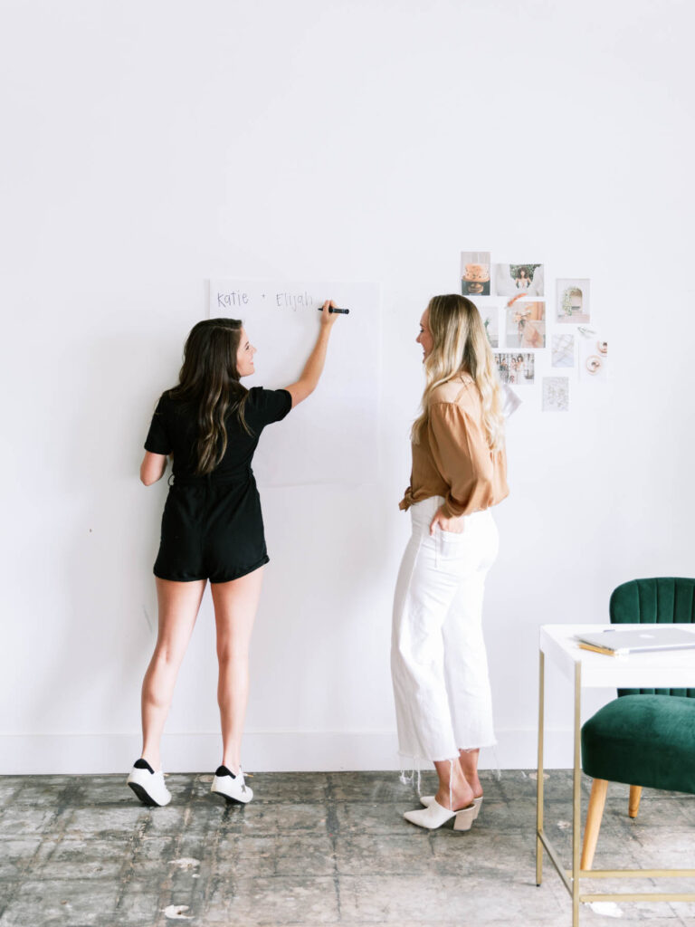 A woman entrepreneur collaborating with a designer over brand visuals and strategy—capturing the partnership between vision, design, and technology.